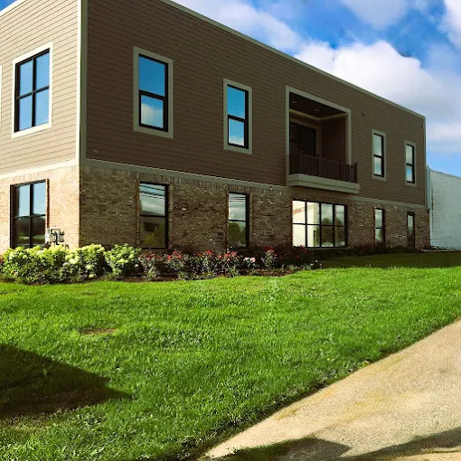 Building exterior with brick and wood siding beside a lawn
